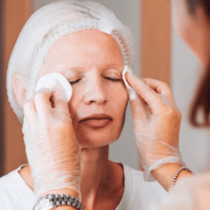 Doctora aplicando limpieza en la cara a mujer con los ojos cerrados